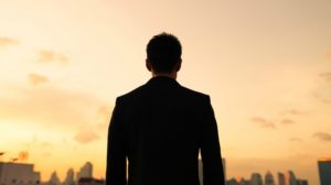 silhouette of man looking at city in suit | Why is Finding Meaning In Life and Work So Important? https://positiveroutines.com/finding-meaning/ 