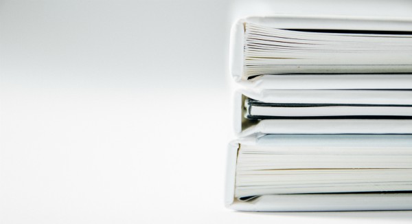 stack of thick folders on white surface | The Best Decluttering Tips for a Productive Workspace https://positiveroutines.com/decluttering-tips/