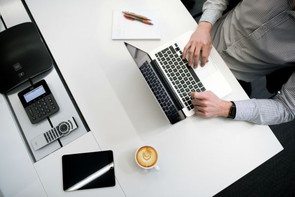 top lay of man working on laptop with coffee | How to Prioritize + 5 Secrets That Make It Easy  https://positiveroutines.com/how-to-prioritize/