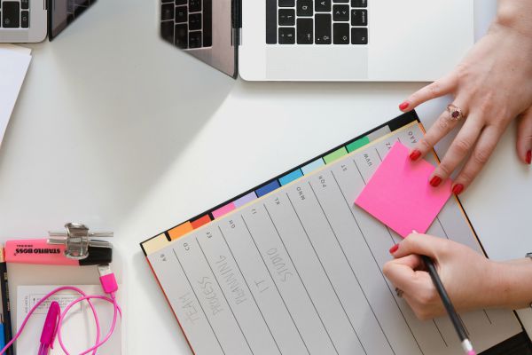 woman writing in planner with pink post-its | New Science Reveals 5 Secrets That Will Make You Happy