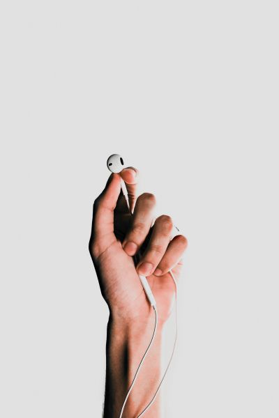 hand holding ear buds | Can You Use Music For Productivity Gains? https://positiveroutines.com/music-for-productivity/