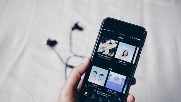 hand holding smartphone displaying spotify | Can You Use Music For Productivity Gains? https://positiveroutines.com/music-for-productivity/