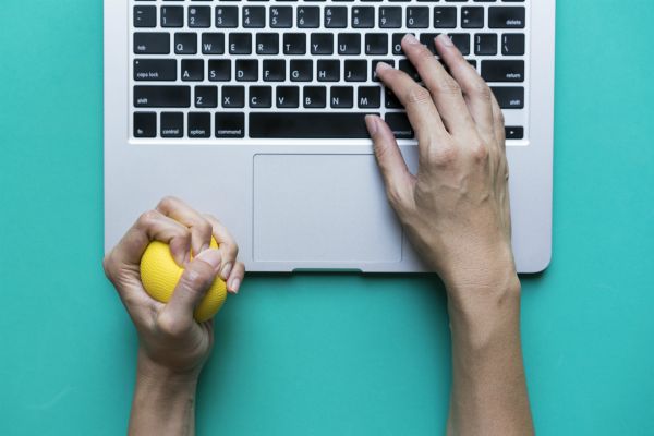 hand holding stress ball while typing on laptop | Feeling stressed out? 46 Ways to Take Control Now https://positiveroutines.com/tips-for-feeling-stressed/