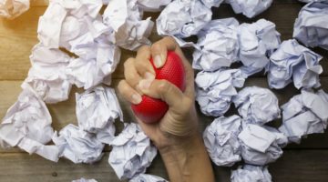 hand squeezing red stress ball with crumpled paper balls | Feeling stressed out? 46 Ways to Take Control Now https://positiveroutines.com/tips-for-feeling-stressed/