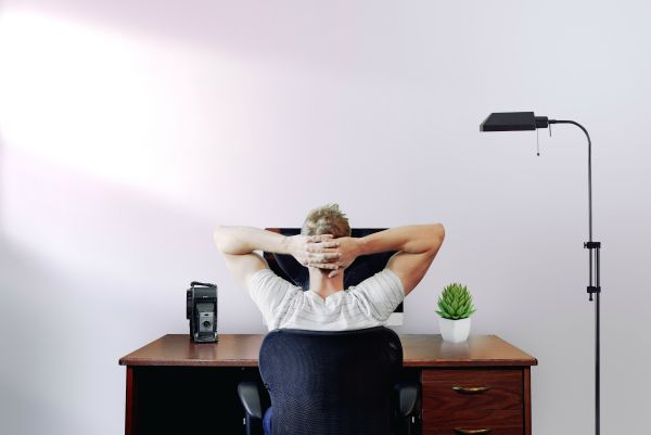 man staring at computer with arms behind his head | Why is Finding Meaning In Life and Work So Important? https://positiveroutines.com/finding-meaning/ 