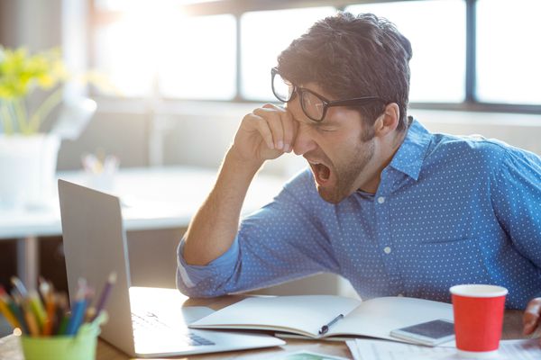 man yawning at desk | How to Handle Job Burnout, Even If You Love Your Work https://positiveroutines.com/job-burnout-guide/