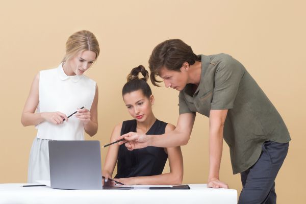 three coworkers looking at laptop screen | How to Handle Job Burnout, Even If You Love Your Work https://positiveroutines.com/job-burnout-guide/