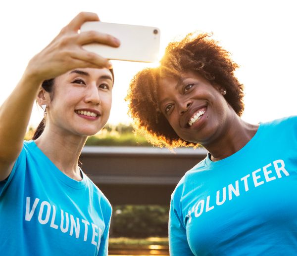 two women with volunteer shirts on taking selfie | Why is Finding Meaning In Life and Work So Important? https://positiveroutines.com/finding-meaning/ 