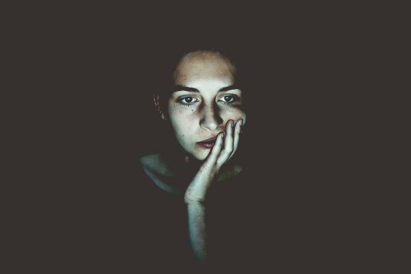 woman looking sad in dark | Can You Use Music For Productivity Gains? https://positiveroutines.com/music-for-productivity/