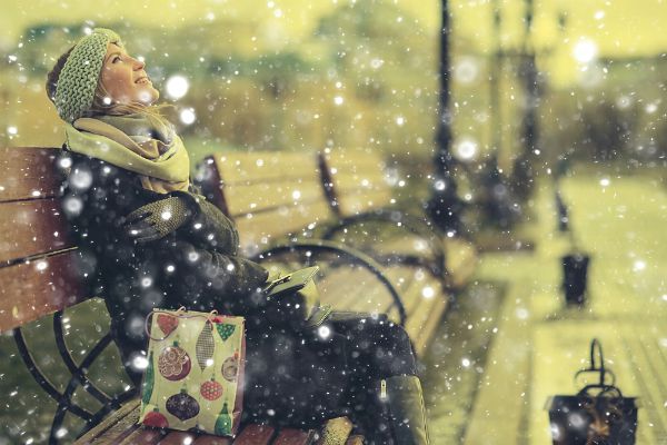 woman sitting on bench looking up at snow smiling | Feeling stressed out? 46 Ways to Take Control Now https://positiveroutines.com/tips-for-feeling-stressed/