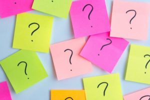 colorful post it noes with question marks on them on white wall | 83 Secrets To Make You Happier At Work https://positiveroutines.com/happier-at-work/