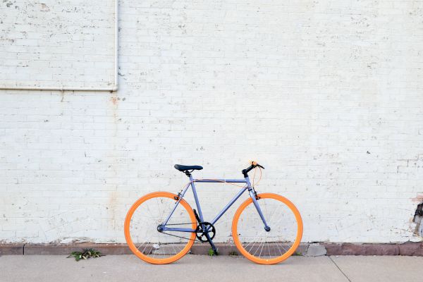 gray bike with yellow tires against white brick wall | How to Make the Most of Your Commute to Work https://positiveroutines.com/commute-to-work-tips/