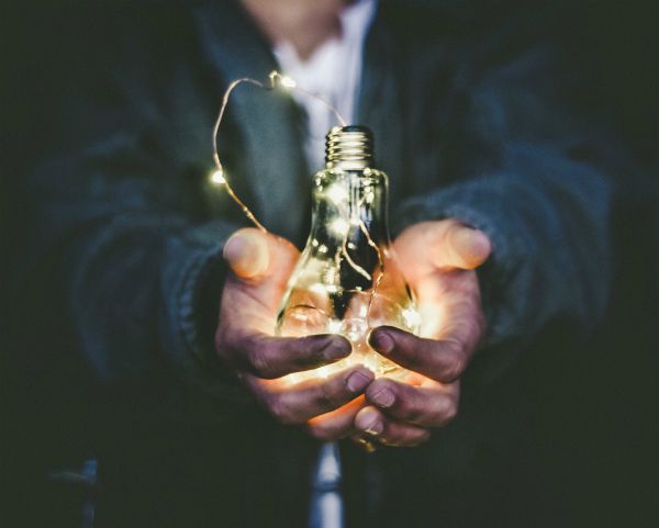 man holding lightbulb lit with string lights | For Ultimate Productivity, Manage Your Energy, Not Your Time  https://positiveroutines.com/manage-your-energy-not-your-time/ 