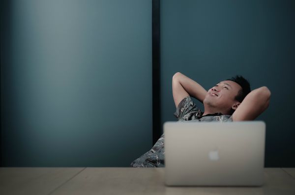 man sitting back relaxing with laptop on desk | In Time for the Holidays: How to Take Breaks Effectively  https://positiveroutines.com/how-to-take-breaks/