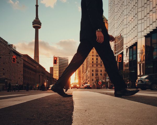 man walking across crosswalk in city | How to Make the Most of Your Commute to Work https://positiveroutines.com/commute-to-work-tips/
