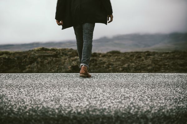 man walking on concrete on cloudy day | How to Make the Most of Your Commute to Work https://positiveroutines.com/commute-to-work-tips/