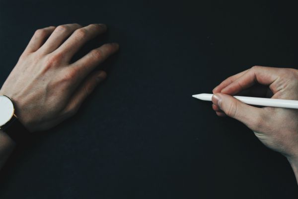man's hands writing on black surface | How to Make the Most of Your Commute to Work https://positiveroutines.com/commute-to-work-tips/