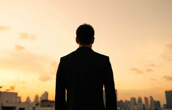 mans silhouette against city skyline in morning | 83 Secrets To Make You Happier At Work https://positiveroutines.com/happier-at-work/