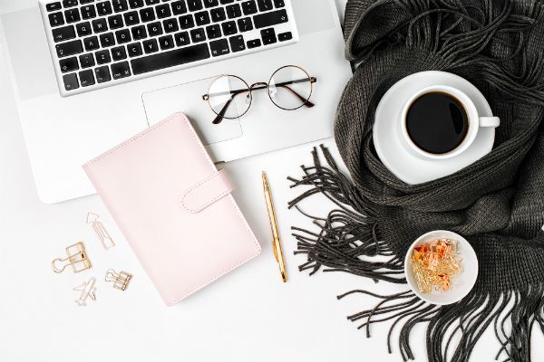 top lay of laptop with glasses scarf and planner | 83 Secrets To Make You Happier At Work https://positiveroutines.com/happier-at-work/