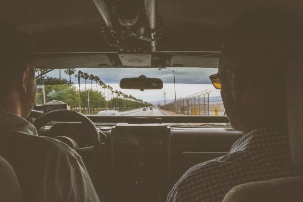 two men in car on highway with palm trees | How to Make the Most of Your Commute to Work https://positiveroutines.com/commute-to-work-tips/