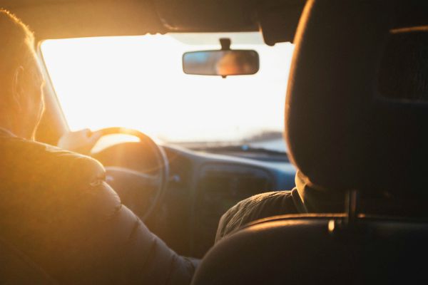 two people in a car against sun | How to Make the Most of Your Commute to Work https://positiveroutines.com/commute-to-work-tips/