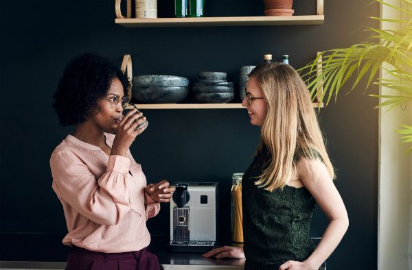 two women talking at coffee machine | 83 Secrets To Make You Happier At Work https://positiveroutines.com/happier-at-work/