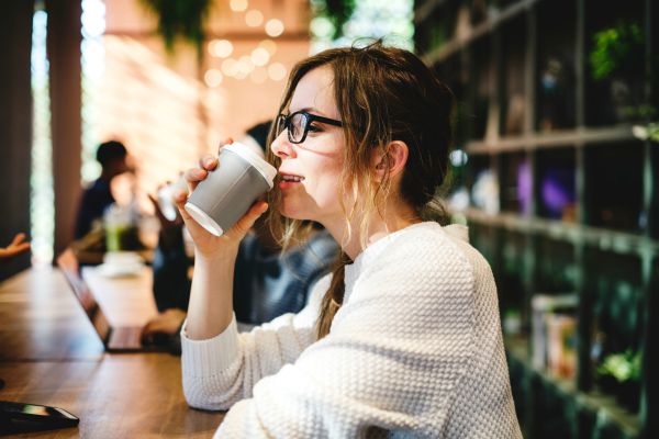 woman drinking coffee in sweater smiling | No Distractions: 5 Ways to Focus This Fall