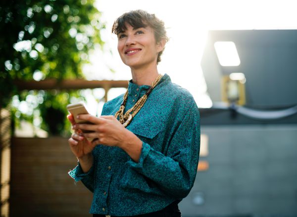 woman smiling while looking at phone | 83 Secrets To Make You Happier At Work https://positiveroutines.com/happier-at-work/