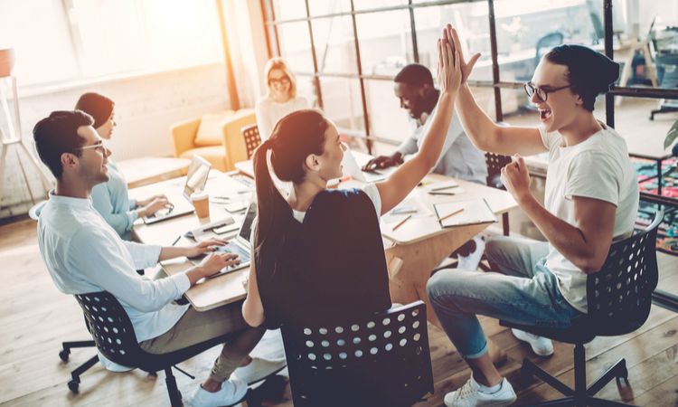 young colleagues high fiving in open office | 83 Secrets To Make You Happier At Work https://positiveroutines.com/happier-at-work/