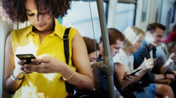 young woman on smartphone on subway morning commute | How to Make the Most of Your Commute to Work https://positiveroutines.com/commute-to-work-tips/