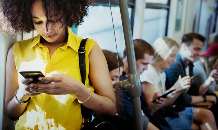 young woman on smartphone on subway morning commute | How to Make the Most of Your Commute to Work https://positiveroutines.com/commute-to-work-tips/