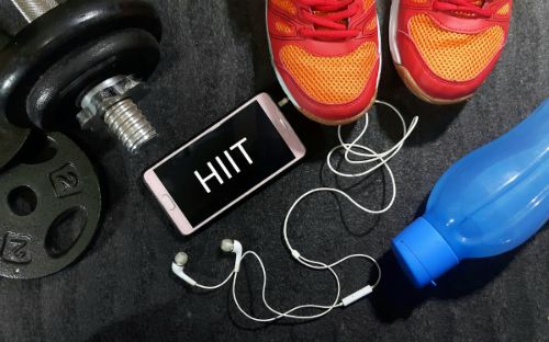 barbell and water bottle and phone displaying hiit on black mat | 67 Healthy Mind and Body Tips to Last You All Winter https://positiveroutines.com/healthy-mind-and-body-tips/