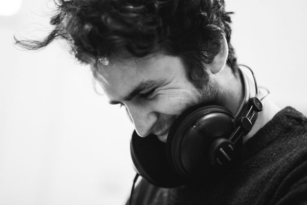 black and white shot of man laughing with headphones around neck | What Are Binaural Beats + Can They Boost Productivity? https://positiveroutines.com/what-are-binaural-beats/ ‎