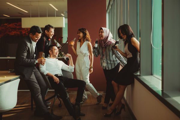 colleagues sharing a drink laughing after work | 7 Surprising Ways to Be Successful at Work https://positiveroutines.com/successful-at-work/