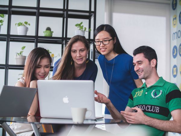 group of young people looking at computer screen | 7 Surprising Ways to Be Successful at Work https://positiveroutines.com/successful-at-work/