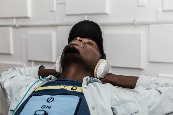 man listening to white headphones leaning back relaxing | What Are Binaural Beats + Can They Boost Productivity? https://positiveroutines.com/what-are-binaural-beats/ ‎