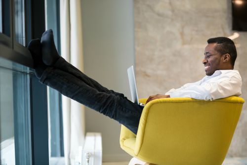 man sitting in yellow chair with feet up on laptop | 67 Healthy Mind and Body Tips to Last You All Winter https://positiveroutines.com/healthy-mind-and-body-tips/