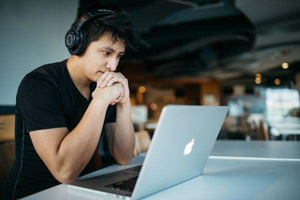 man with headphones looking a laptop stressed | What Are Binaural Beats + Can They Boost Productivity? https://positiveroutines.com/what-are-binaural-beats/ ‎