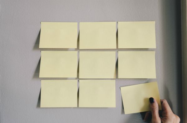 three by three grid of post its on wall woman taking one | This Is How To Express Gratitude https://positiveroutines.com/express-gratitude/