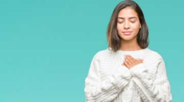 woman in white sweater holding hands over heart gratitude concept | 5 Simple Steps to Feeling Grateful Right Now https://positiveroutines.com/feeling-grateful/