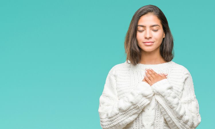 woman in white sweater holding hands over heart gratitude concept | 5 Simple Steps to Feeling Grateful Right Now https://positiveroutines.com/feeling-grateful/