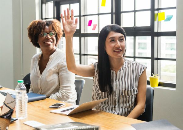 woman raising hand at meeting | 7 Surprising Ways to Be Successful at Work https://positiveroutines.com/successful-at-work/