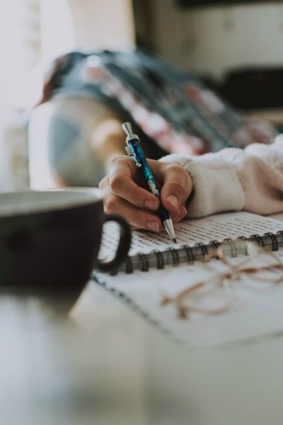 woman writing in journal with pen and coffee | How to Practice Gratitude With Us This November  https://positiveroutines.com/practice-gratitude/