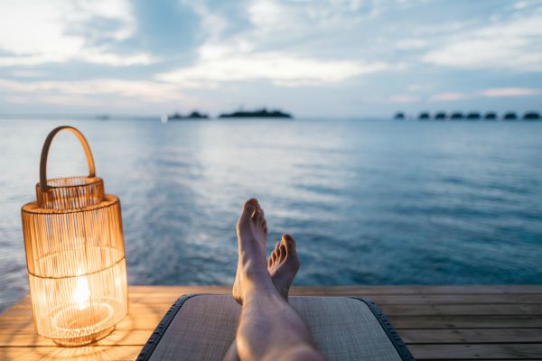 mans legs on dock overlooking water sunset | The Unmistakable Magic of The 4 Day Week https://positiveroutines.com/four-day-week/