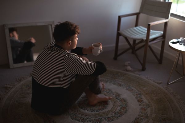 pensive male sitting on floor with cup of coffee | A Healthy Morning Routine For The Best 2019 https://positiveroutines.com/healthy-morning-routine/