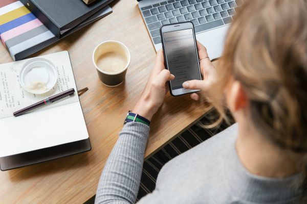woman checking phone at desk | How To Get Focused In The Morning https://positiveroutines.com/get-focused/