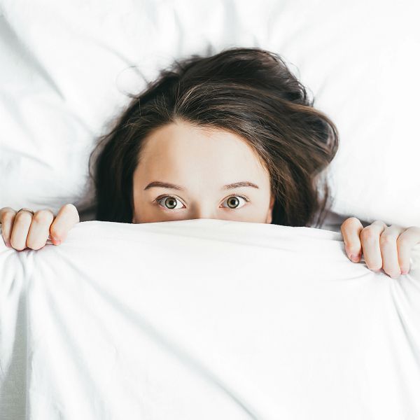 woman in bed with covers pulled up eyes open | 11 Free Sleep Apps for the Best Nights This Season https://positiveroutines.com/free-sleep-apps/