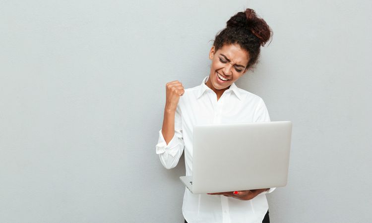 woman in white shirt holding laptop smiling | The Happiest Stories of 2018 to Get You in The Spirit https://positiveroutines.com/happiest-stories/