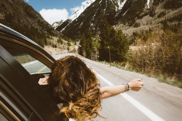 woman leaning out car window looking at mountains | The Unmistakable Magic of The 4 Day Week https://positiveroutines.com/four-day-week/