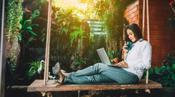 female relaxing on outdoor swing using laptop | How to Work Remotely + Why You Should Try It This Year https://positiveroutines.com/how-to-work-remotely/